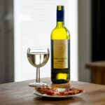 a wine glass and bottle near the pizza on a ceramic plate