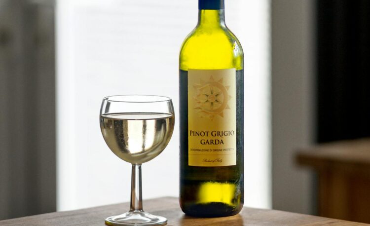 a wine glass and bottle near the pizza on a ceramic plate